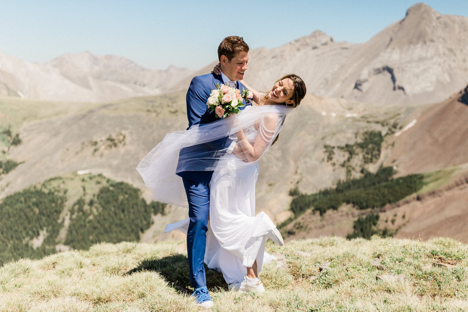 A joyful couple celebrating their wedding outdoors with stunning mountain scenery in the background.