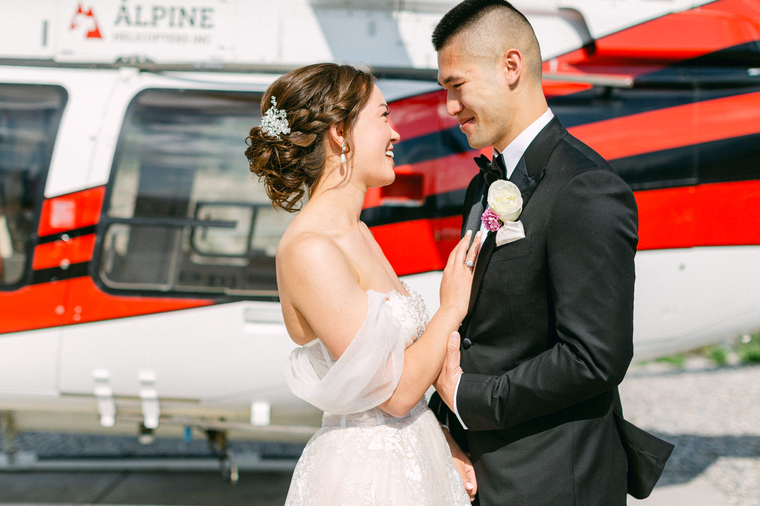 A bride and groom share an intimate moment outside a helicopter, radiating love and joy in their elegant attire.