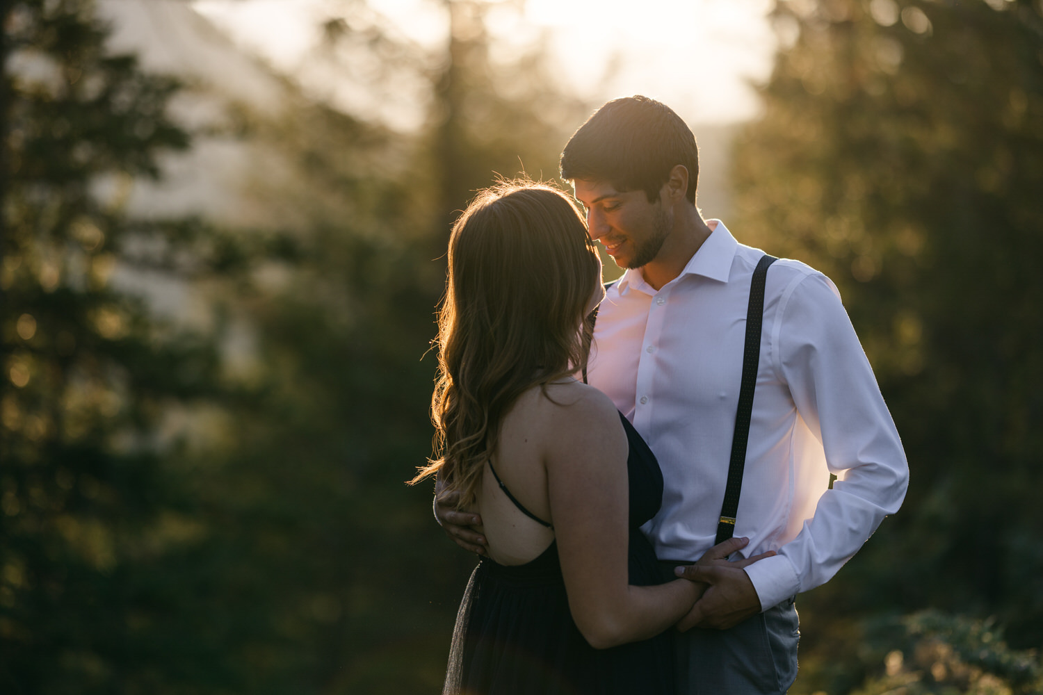 A couple sharing a romantic moment during sunset, surrounded by trees, capturing a sense of love and connection.