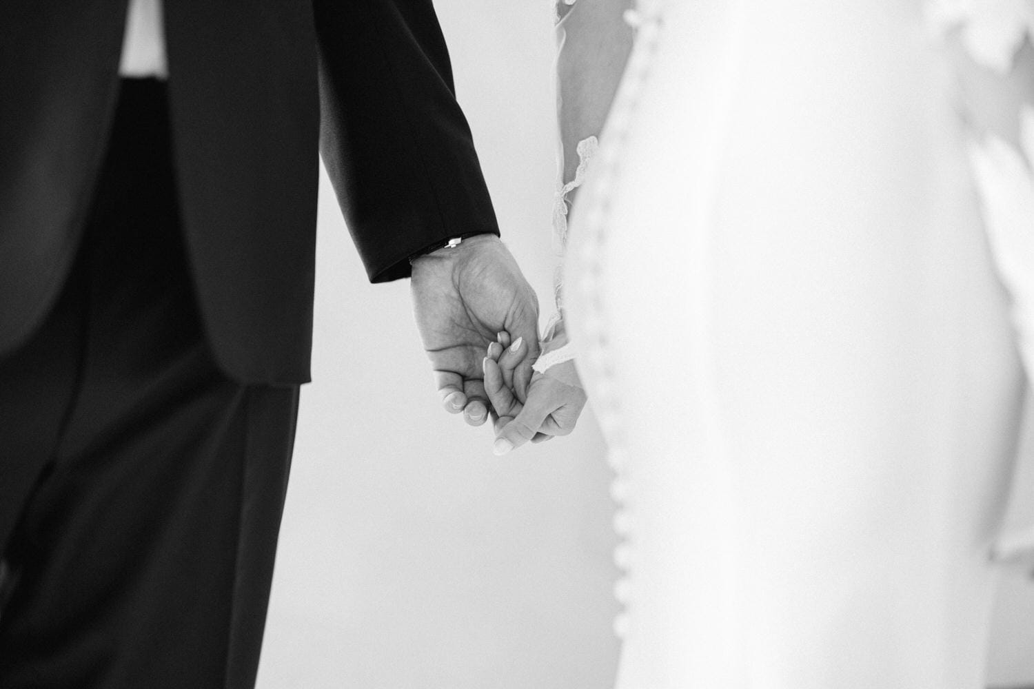 A close-up of a couple holding hands, symbolizing love and unity, captured in a romantic black and white style.