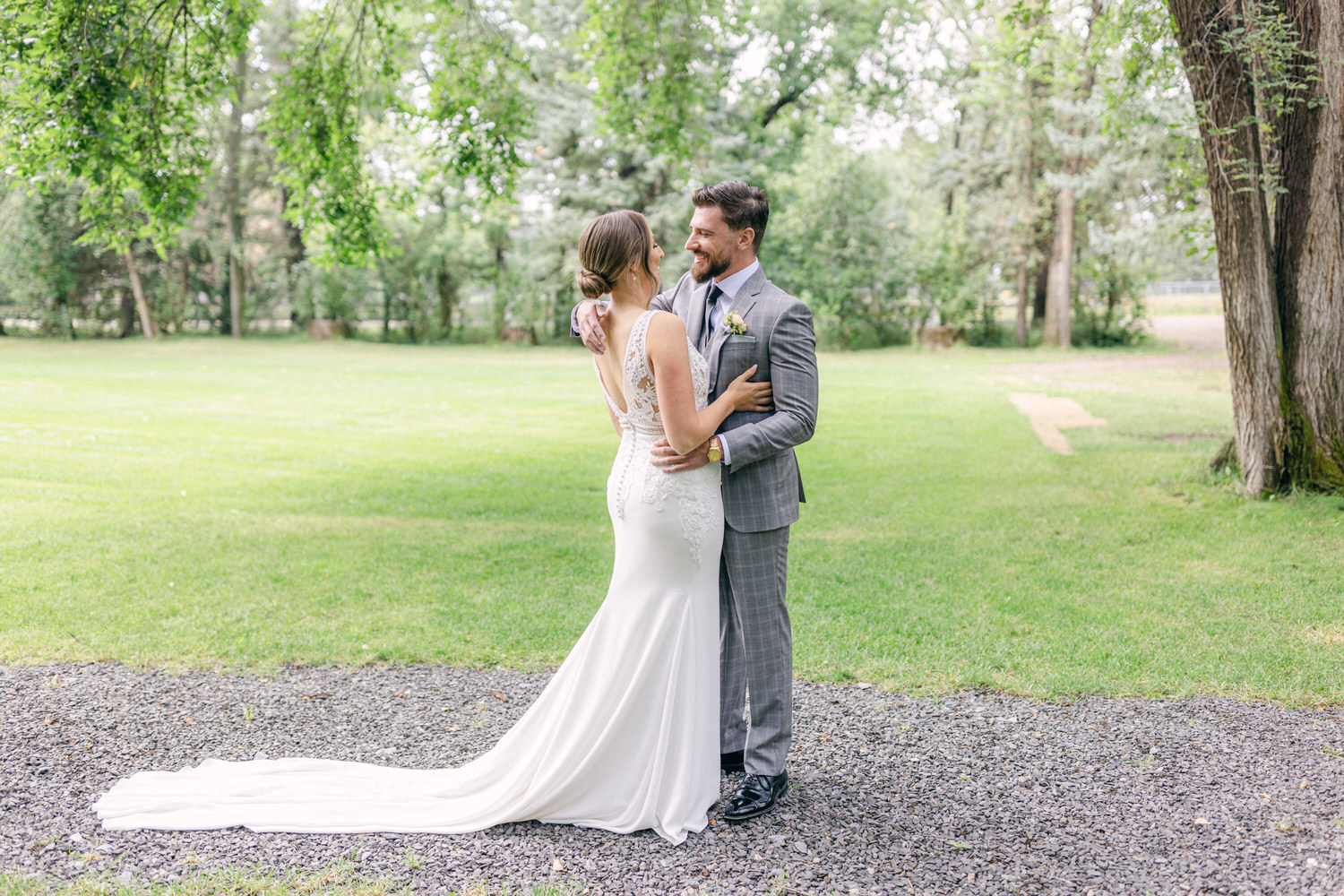 Wedding Bliss in Nature::A groom embracing his bride in a beautiful outdoor setting, surrounded by lush greenery and soft sunlight.