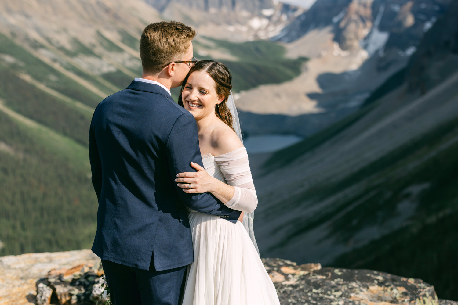 A couple shares a joyful embrace in a scenic mountain setting, highlighting their love and happiness on their wedding day.