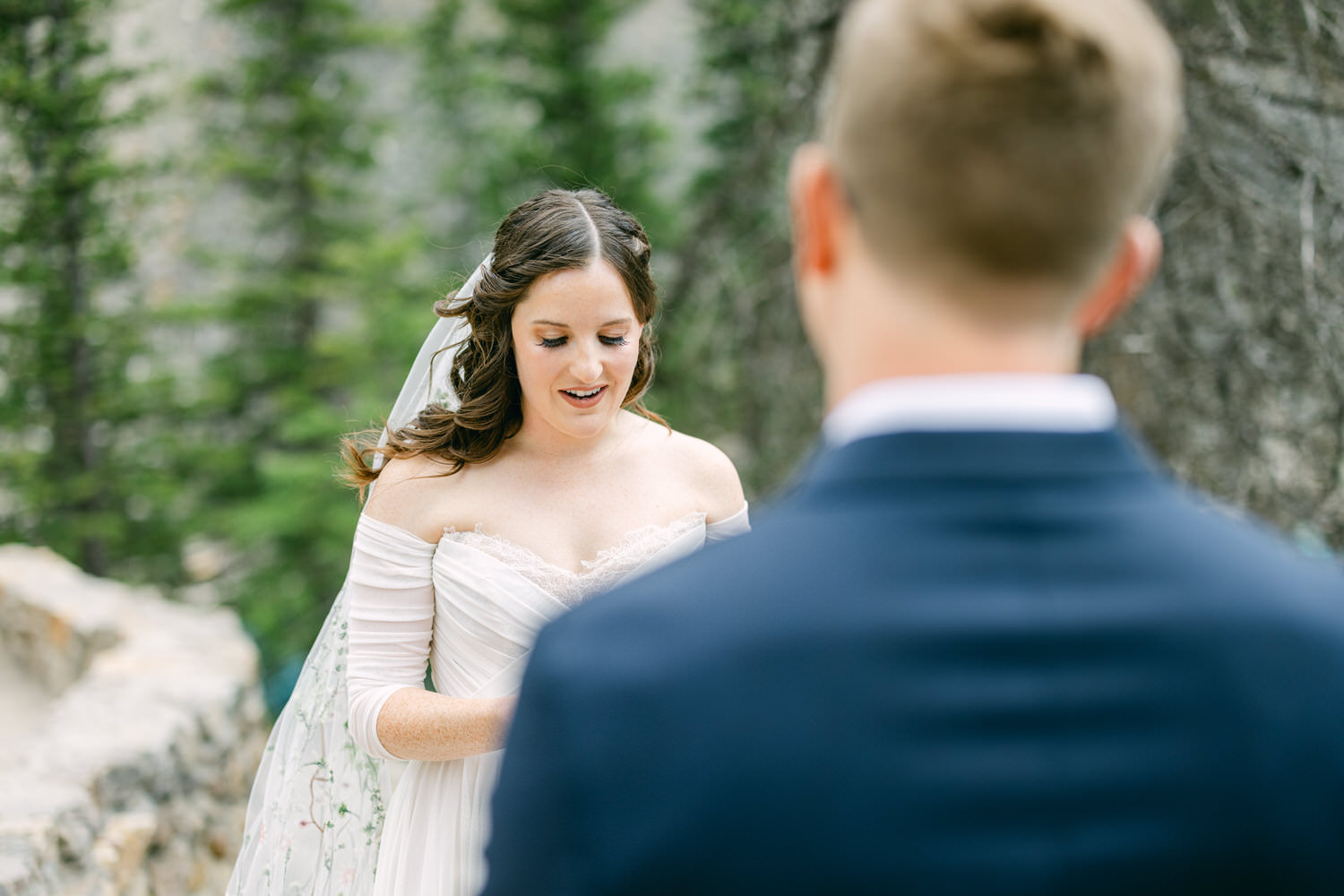 Wedding Ceremony Moment::A bride reading her vows to her groom in a serene outdoor setting surrounded by trees.