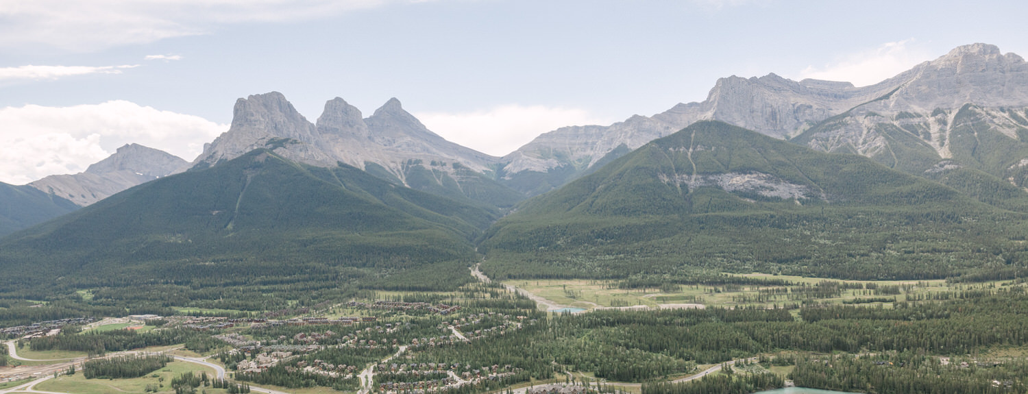 Panoramic view of rugged mountains and verdant hills, showcasing a serene valley with scattered settlements and a winding river.