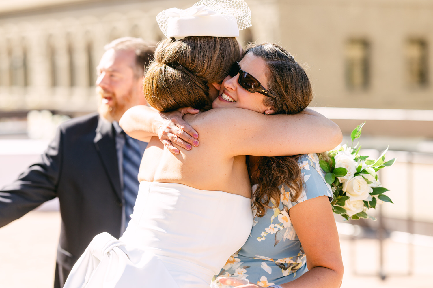 A bride and her friend share a heartfelt hug during a wedding celebration, capturing the warmth and joy of the moment.