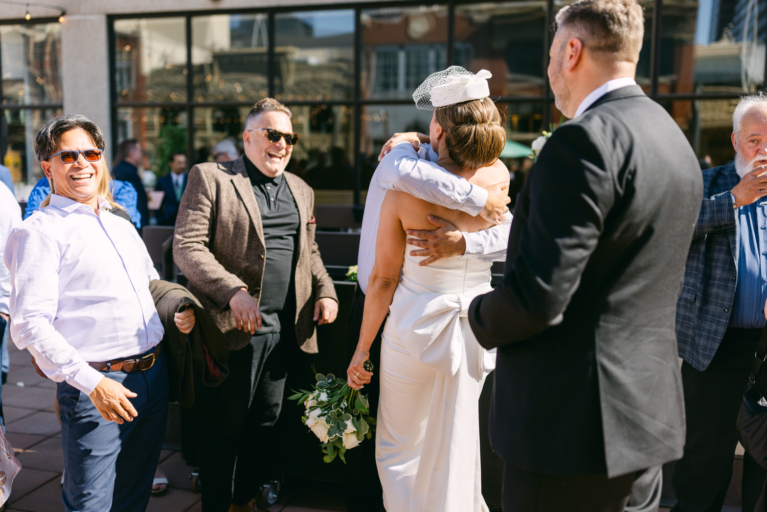 A joyful scene capturing a bride embracing a guest, surrounded by smiling attendees in a festive outdoor setting.