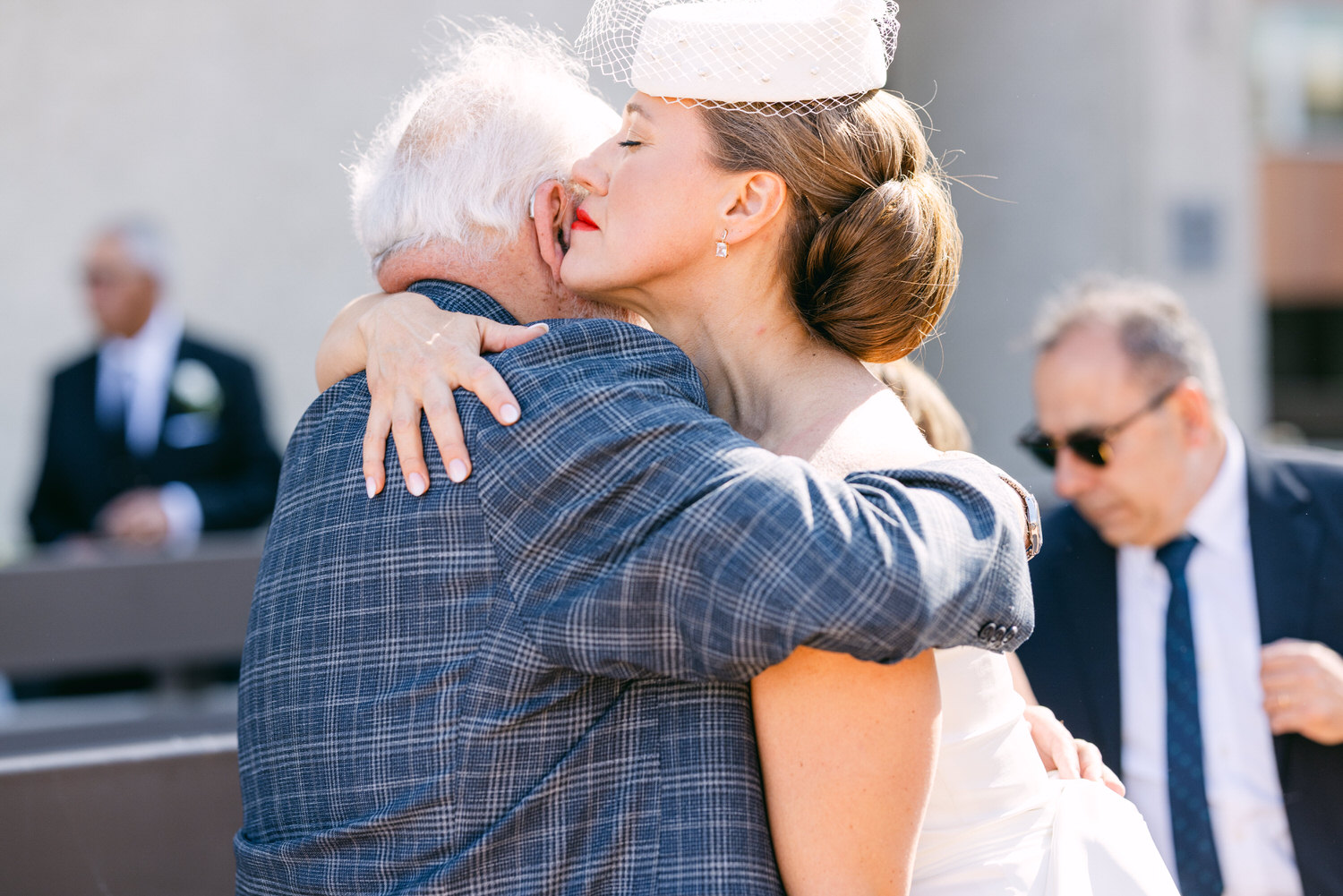 A bride embraces a man in a plaid suit, expressing love and warmth during a wedding celebration.