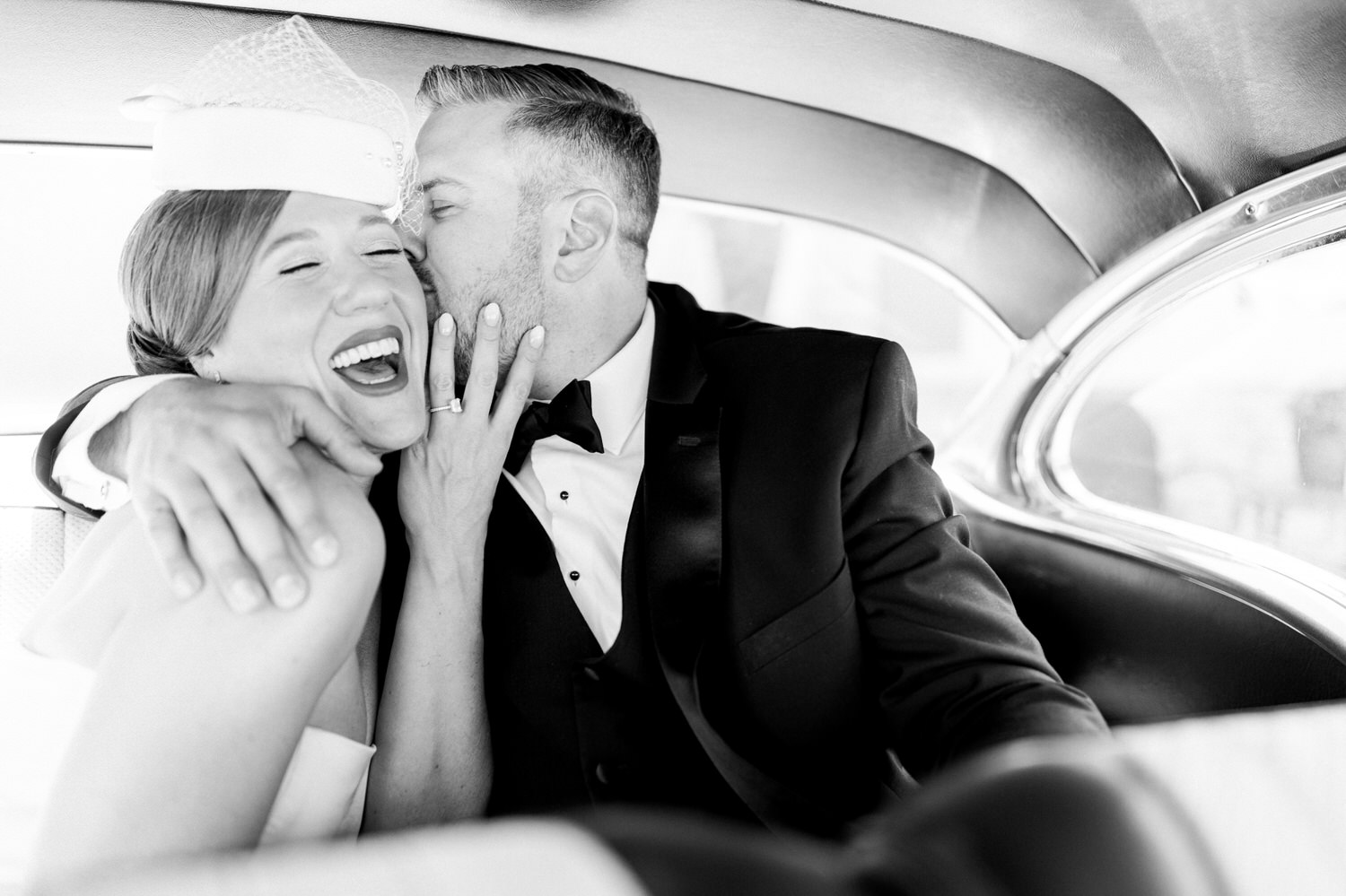 A happy couple sharing a loving moment inside a vintage car, laughing and embracing each other.