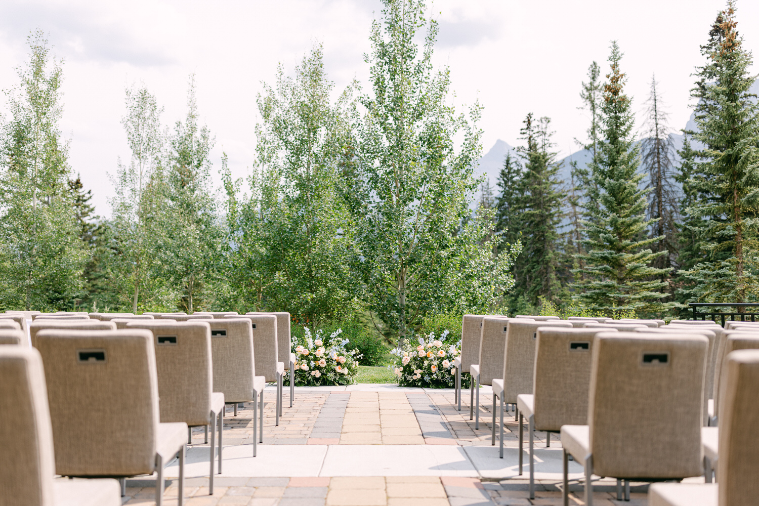 A picturesque scene featuring rows of elegant chairs arranged for an outdoor wedding ceremony, surrounded by lush greenery and floral arrangements.