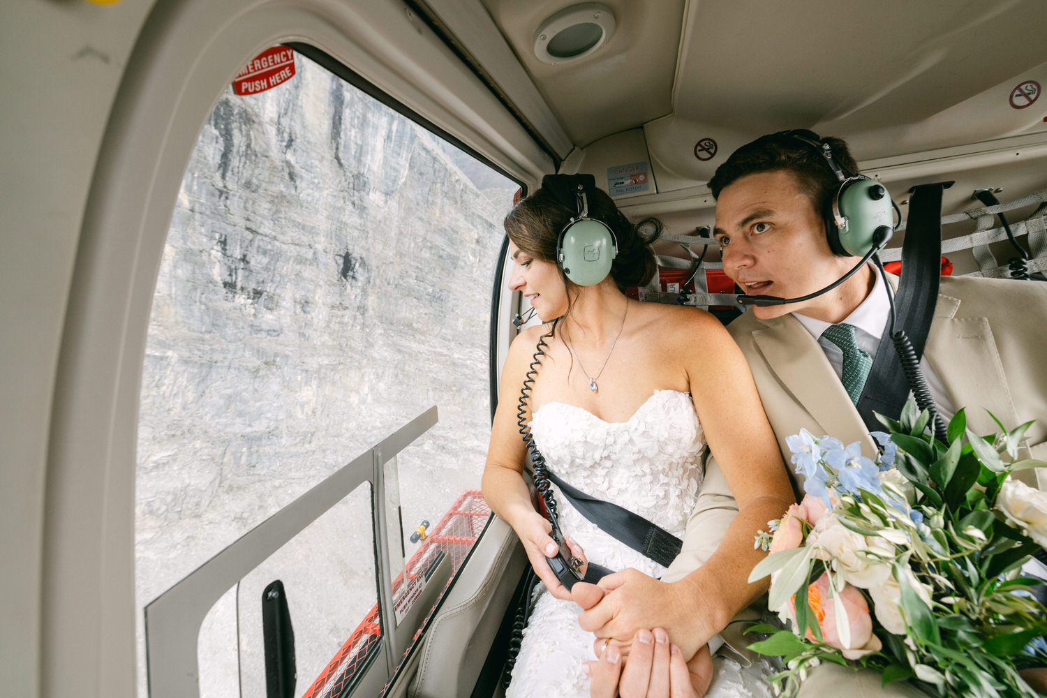 A bride and groom sharing a moment while flying in a helicopter, showcasing the stunning landscape outside the window.