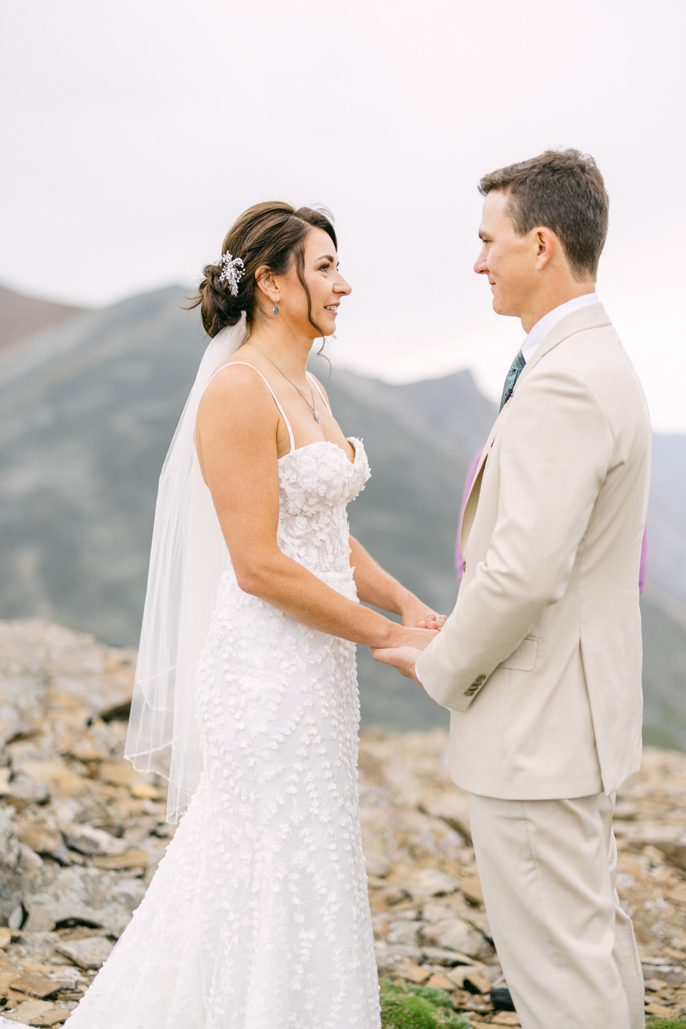 A couple sharing a heartfelt exchange during their wedding ceremony on a scenic mountain backdrop.