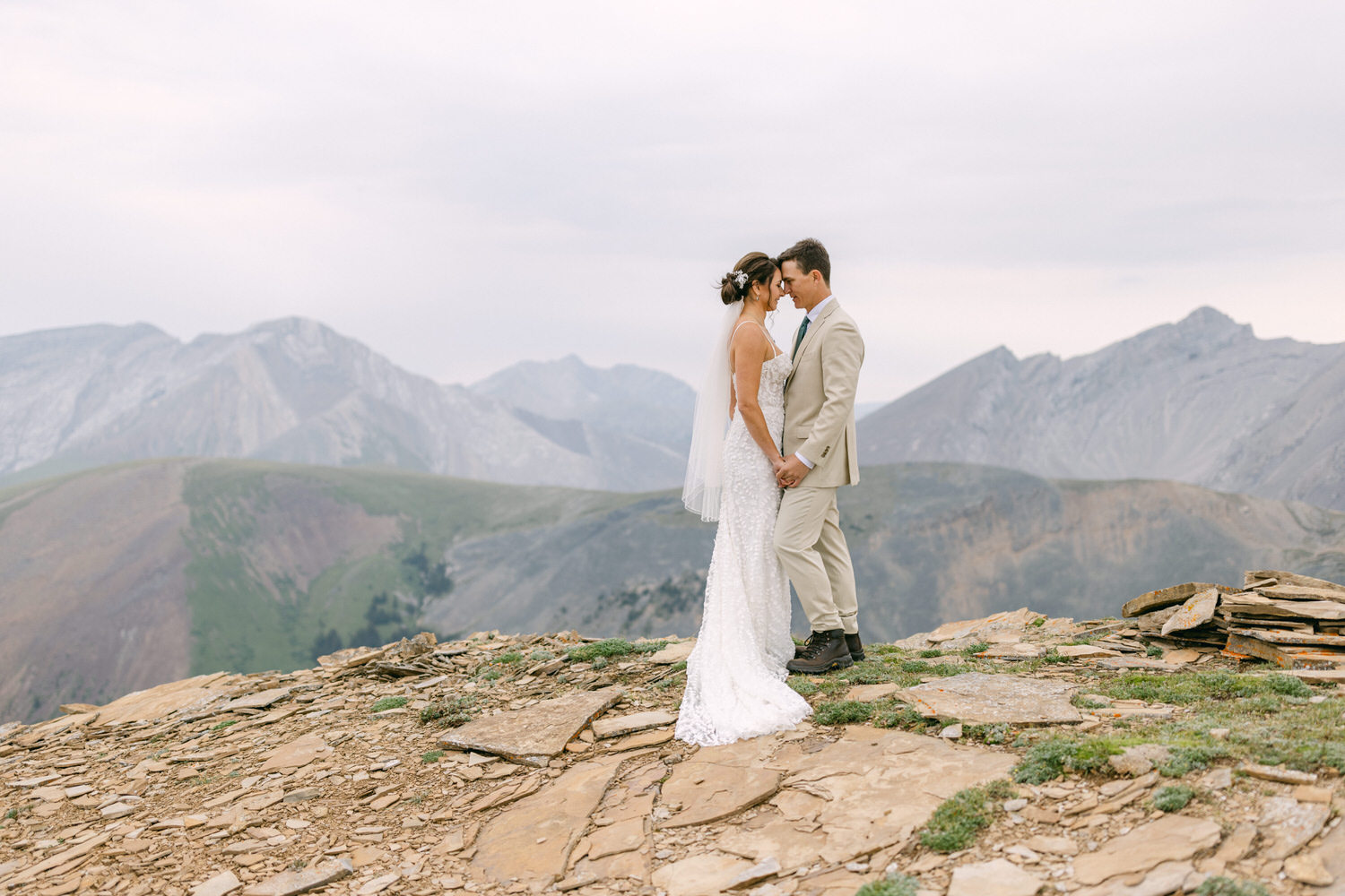 Couple exchanging a loving gaze on a mountain peak, surrounded by breathtaking landscapes.