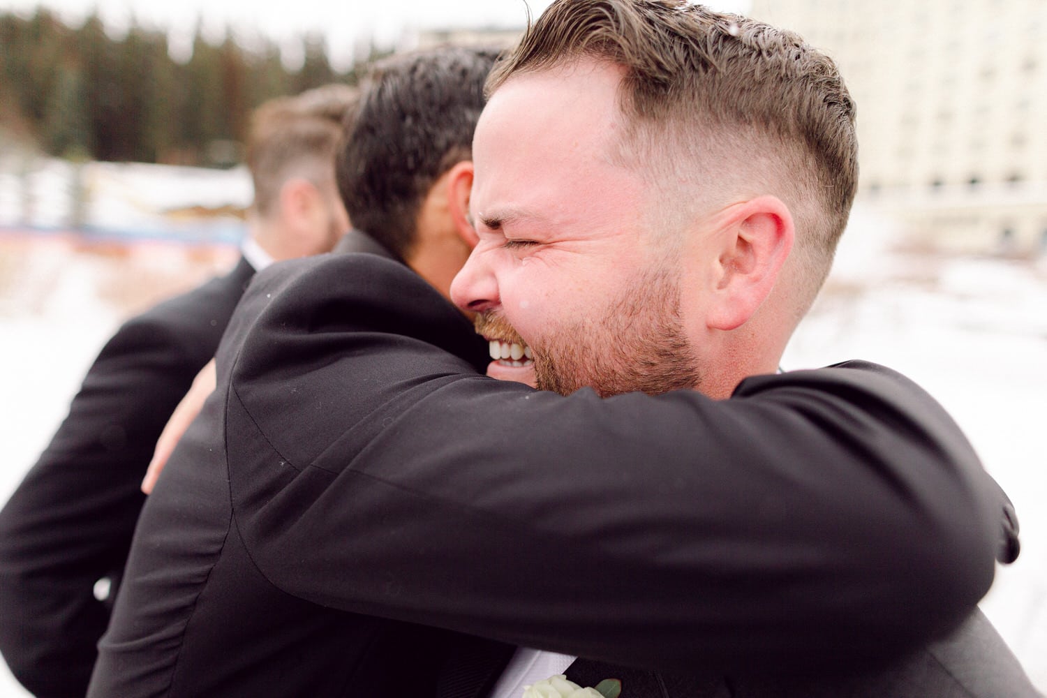 A heartfelt embrace between two men in formal attire, surrounded by a snowy landscape, capturing a moment of happiness and connection.