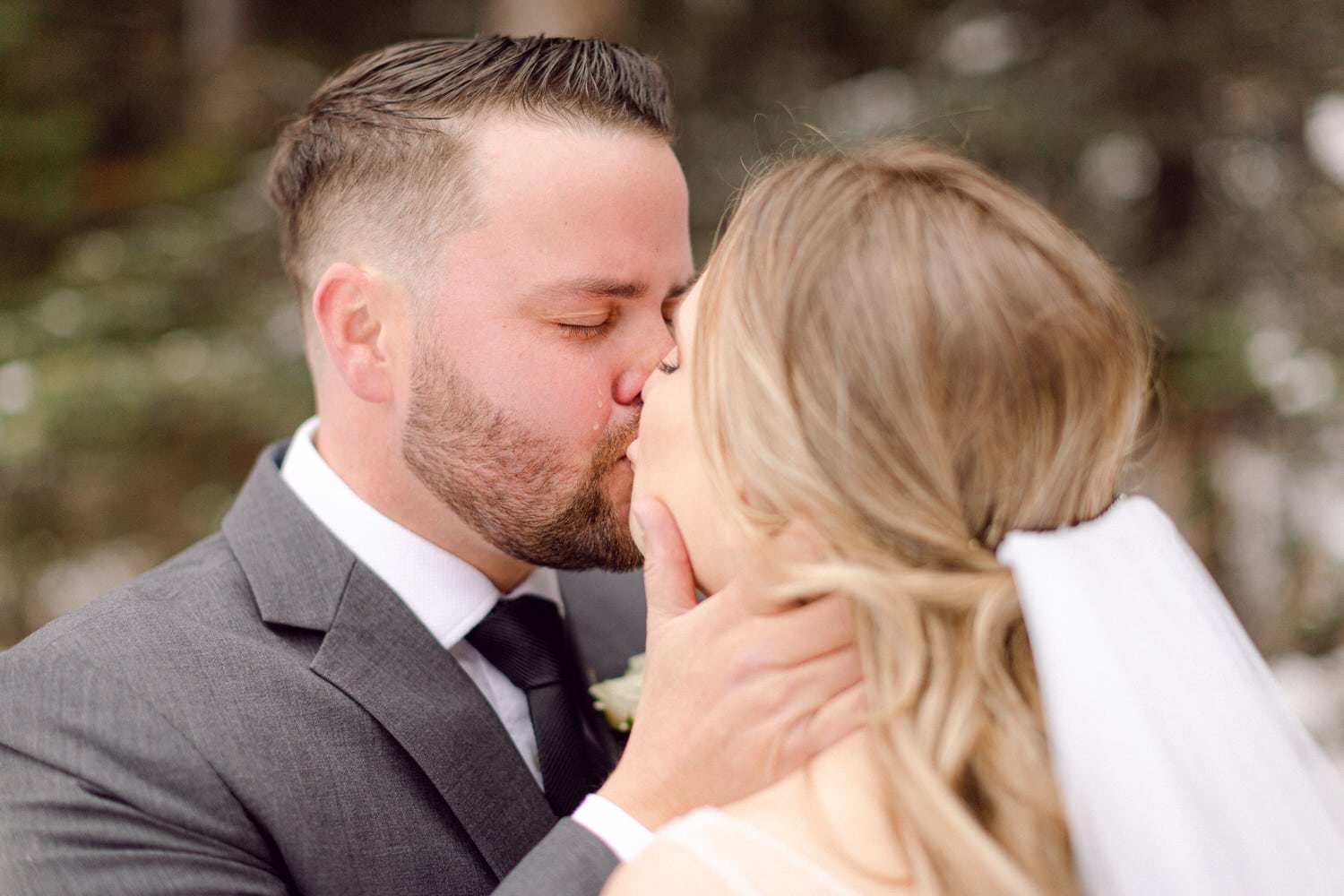 A couple sharing a romantic kiss in a serene outdoor setting, capturing the essence of their love on their special day.