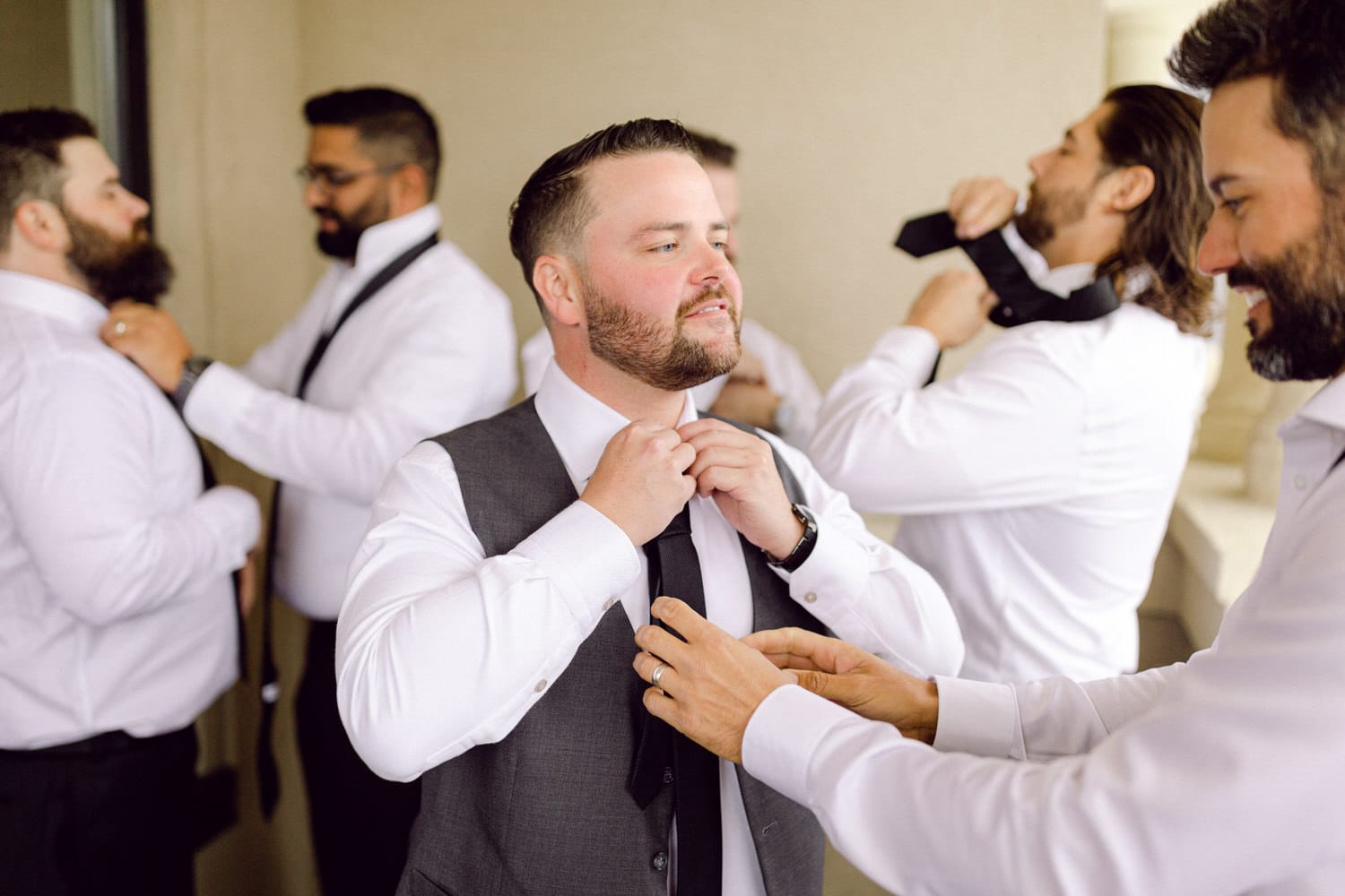 A group of well-dressed men adjusting ties and getting ready for a wedding, showcasing camaraderie and celebration.