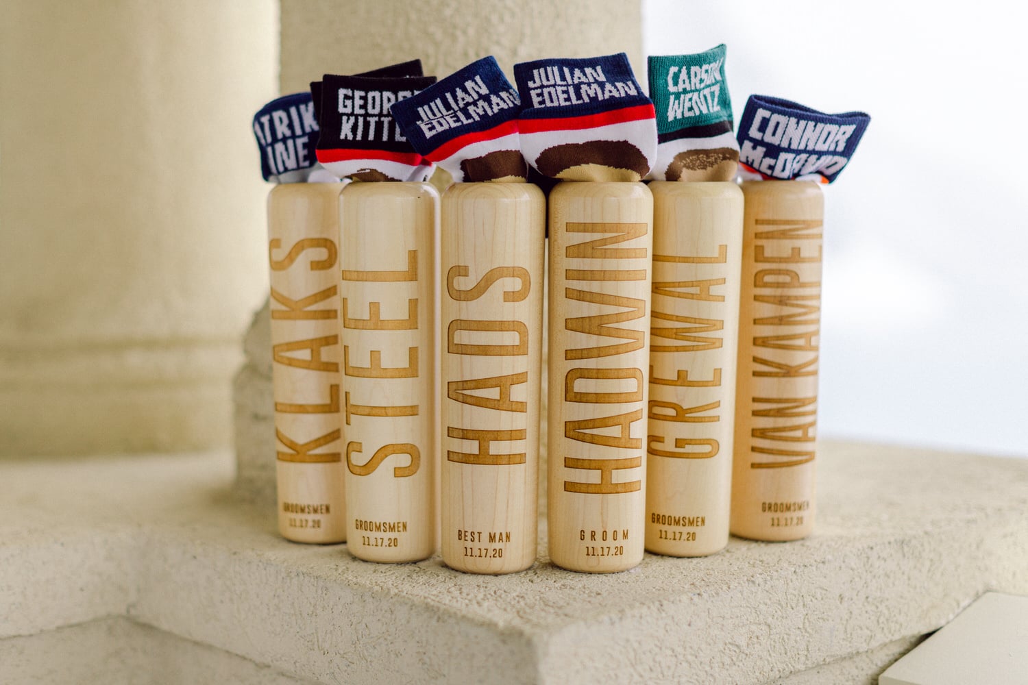 A collection of engraved wooden items representing groomsmen, featuring colorful decorative socks labeled with names.