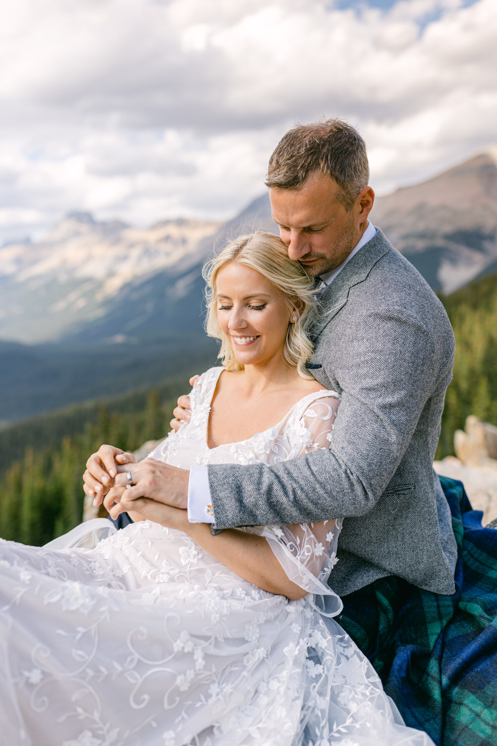 A joyful couple embraces outdoors against a stunning mountain backdrop, showcasing love and happiness in a serene setting.