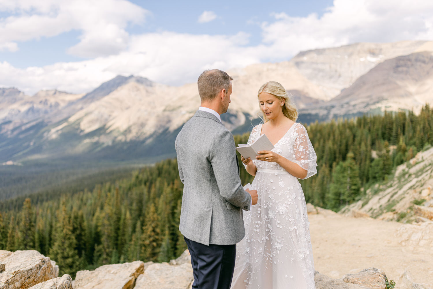 A couple exchanges vows during an intimate outdoor wedding ceremony with a scenic mountain backdrop.