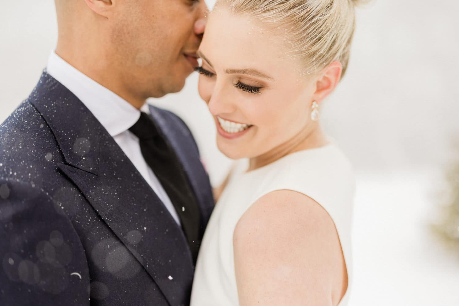 A couple smiling and embracing in a snowy setting, showcasing love and happiness.