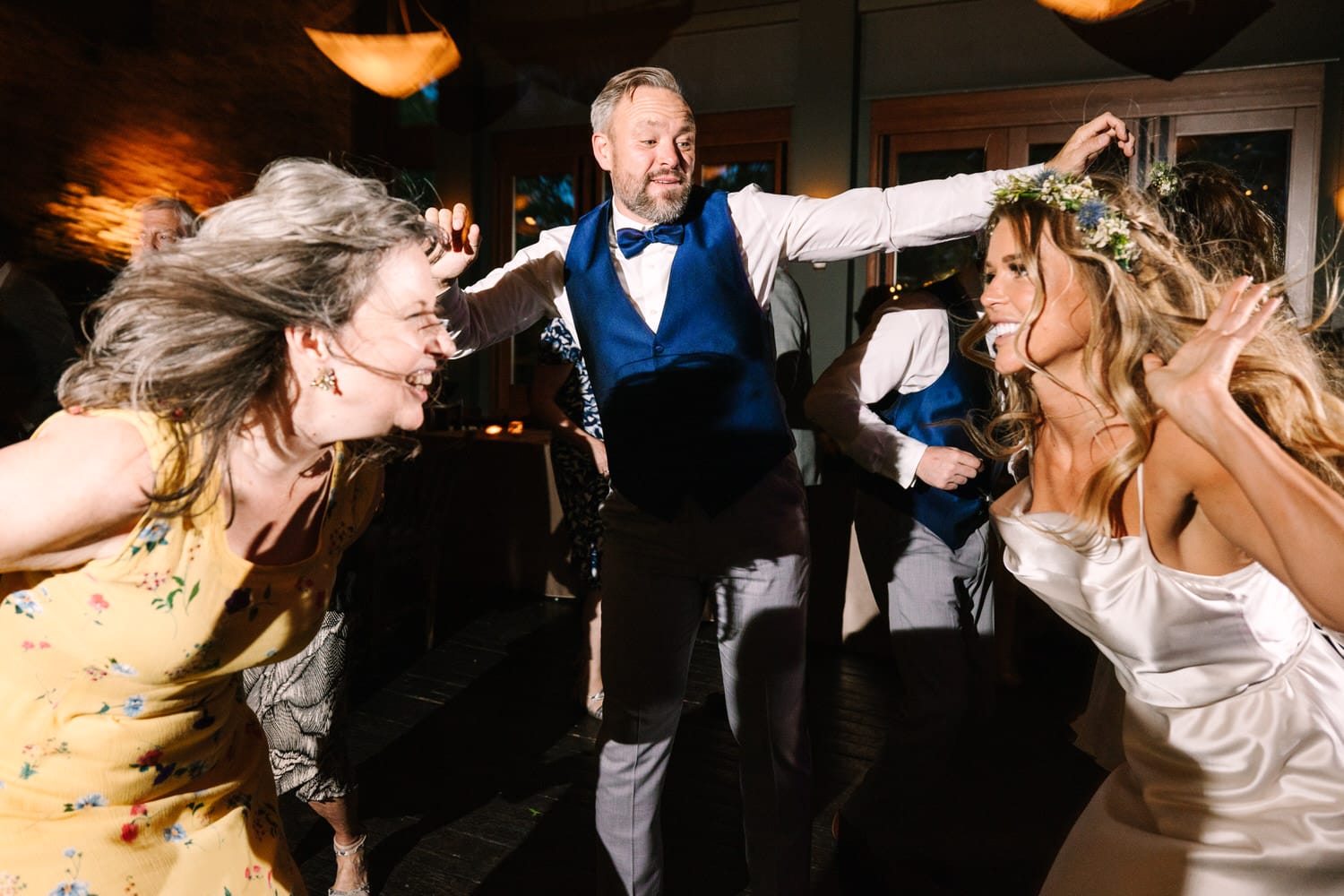 A joyful group of guests dancing enthusiastically at a wedding reception, showcasing vibrant expressions and elegant attire in a lively atmosphere.