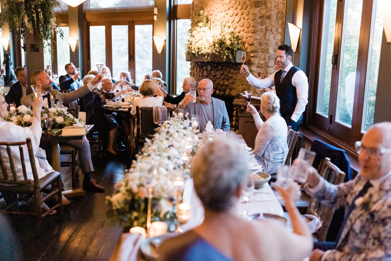 Guests raise their glasses in a toast during a lively reception, surrounded by elegant decor and warm lighting.