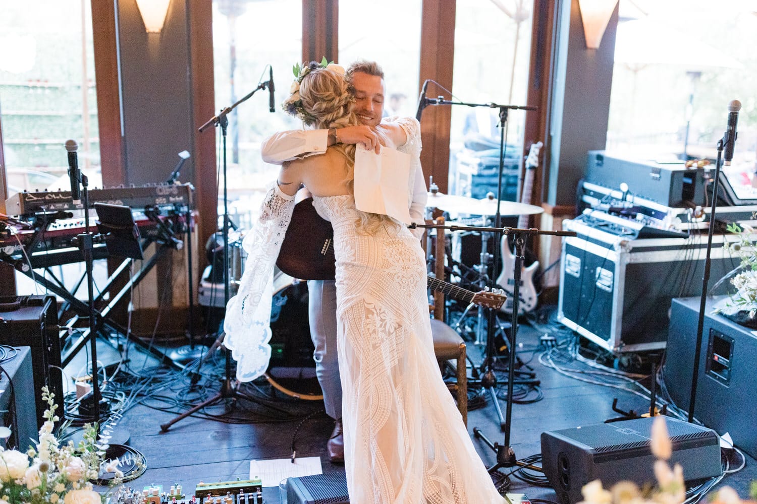 A joyful embrace between a bride and groom during a wedding reception, surrounded by musical instruments and a warm atmosphere.