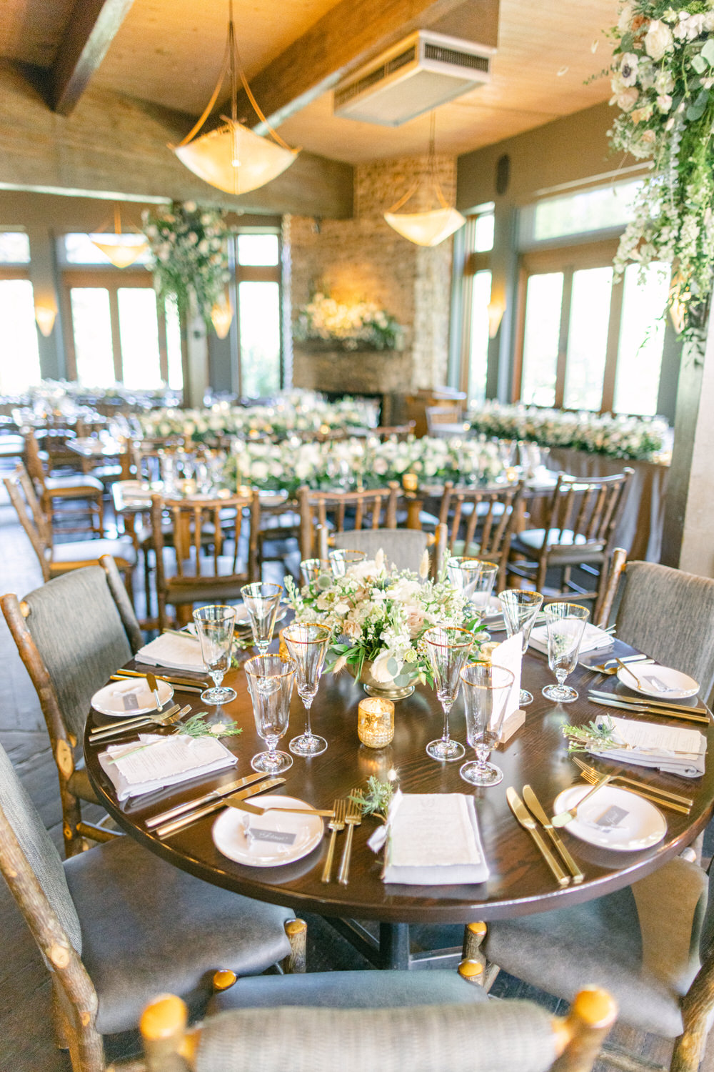 A thoughtfully arranged dining table with floral centerpiece, surrounded by elegant decor and seating in a well-lit event space.