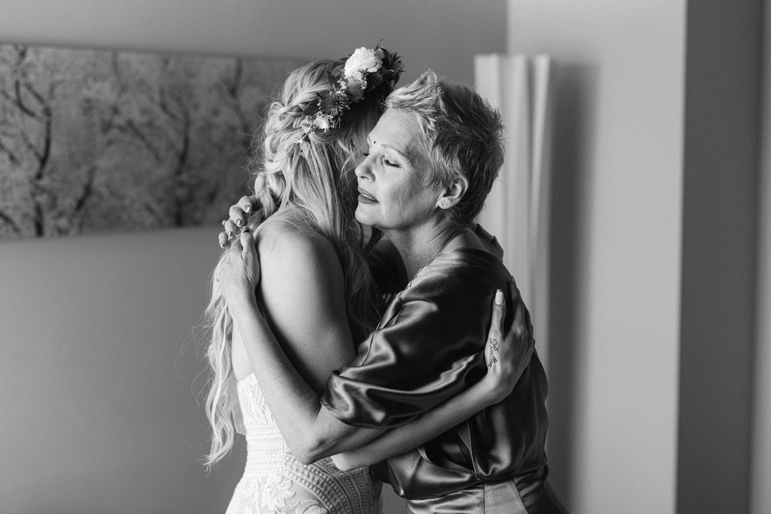 A touching black and white photograph of a bride and her mother sharing a heartfelt hug, showcasing moments of love and connection.