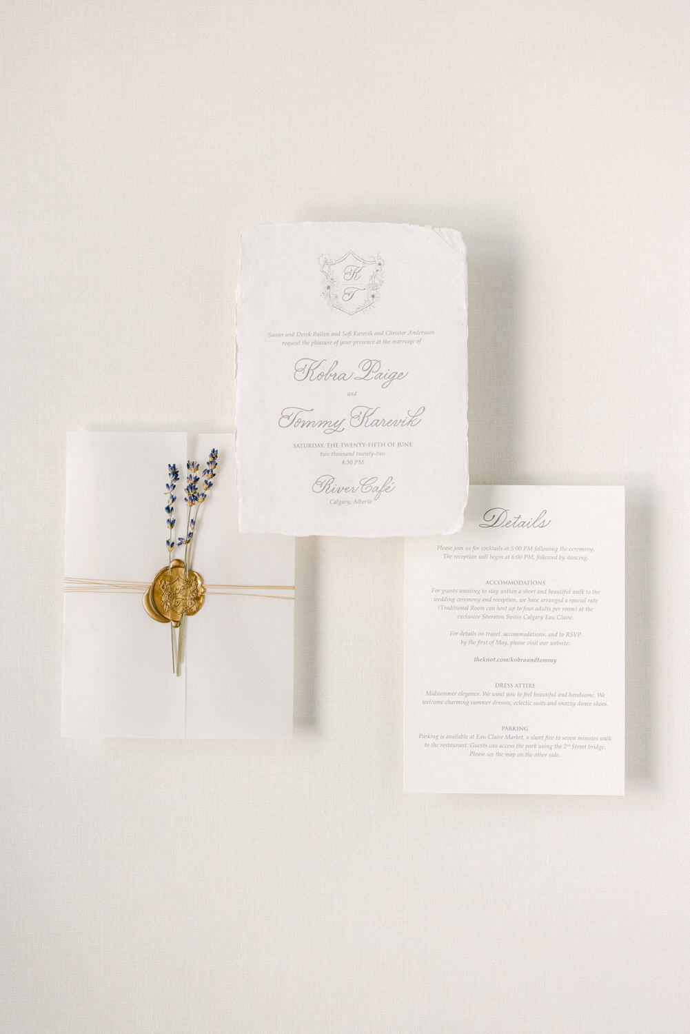 A beautifully arranged wedding invitation suite, featuring a main card with names, date, and venue, along with a formal details card and a wax-sealed envelope adorned with dried lavender.