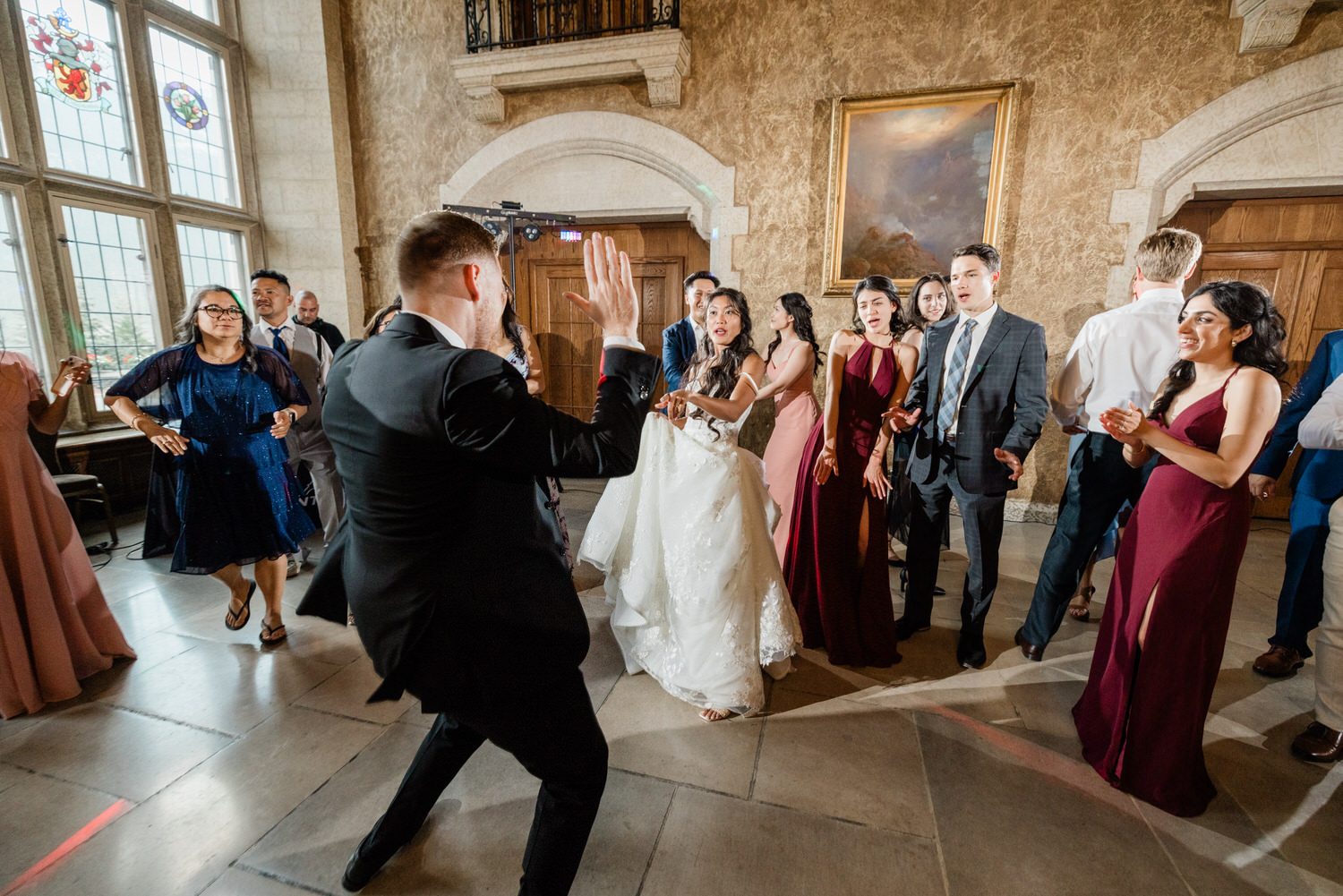 A lively wedding reception scene with guests dancing and enjoying the moment in a beautifully decorated hall.