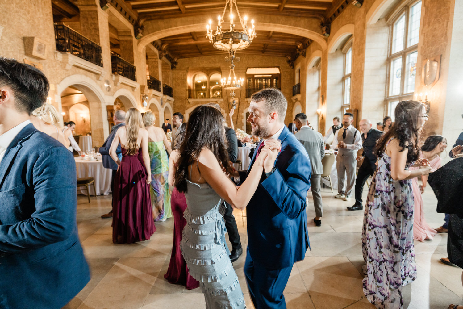 A lively ballroom filled with guests dancing and enjoying a festive atmosphere, featuring elegant decor and vibrant outfits.