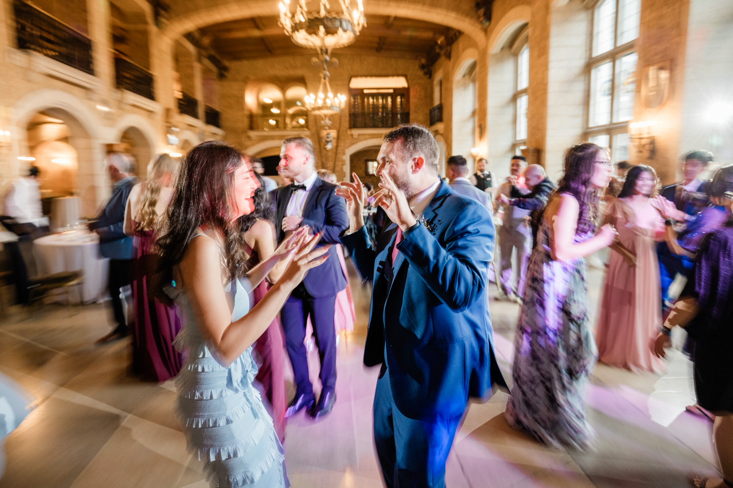 Guests enjoying a lively dance floor at a beautifully lit indoor event, surrounded by elegant décor.