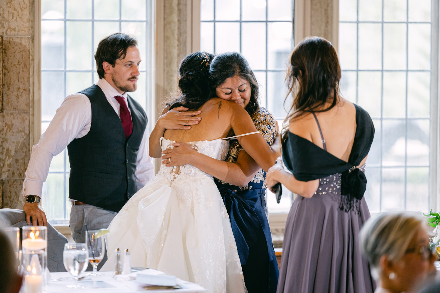 A bride shares a heartfelt hug with her loved ones during a celebration, surrounded by joyful guests.