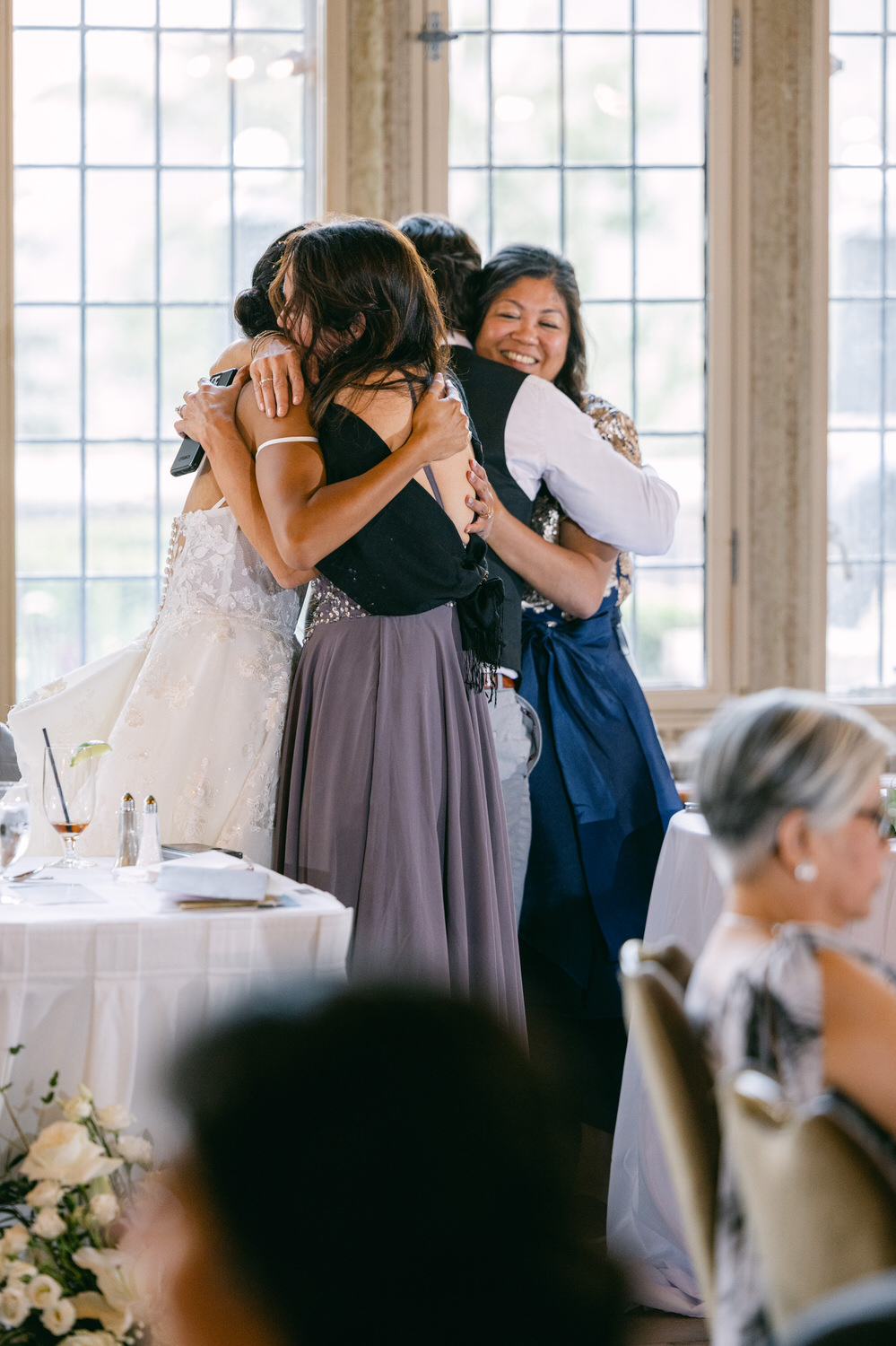 Guests sharing joyful hugs during a wedding reception, showcasing love and connection in a beautifully decorated venue.