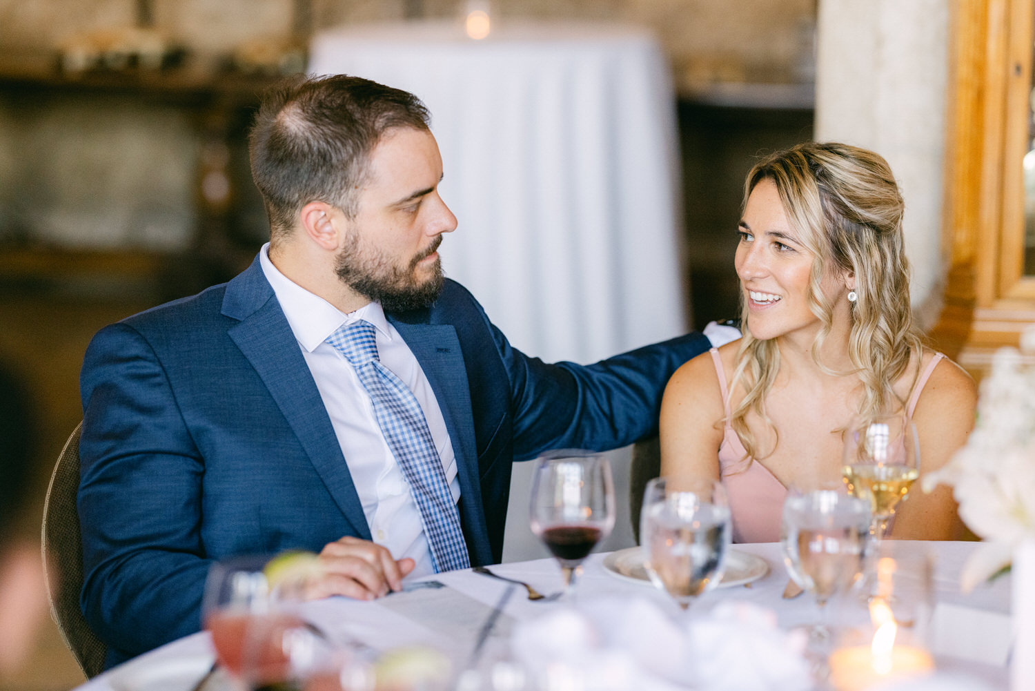 A couple sharing a warm conversation at a beautifully set table, surrounded by drinks and elegant decor.