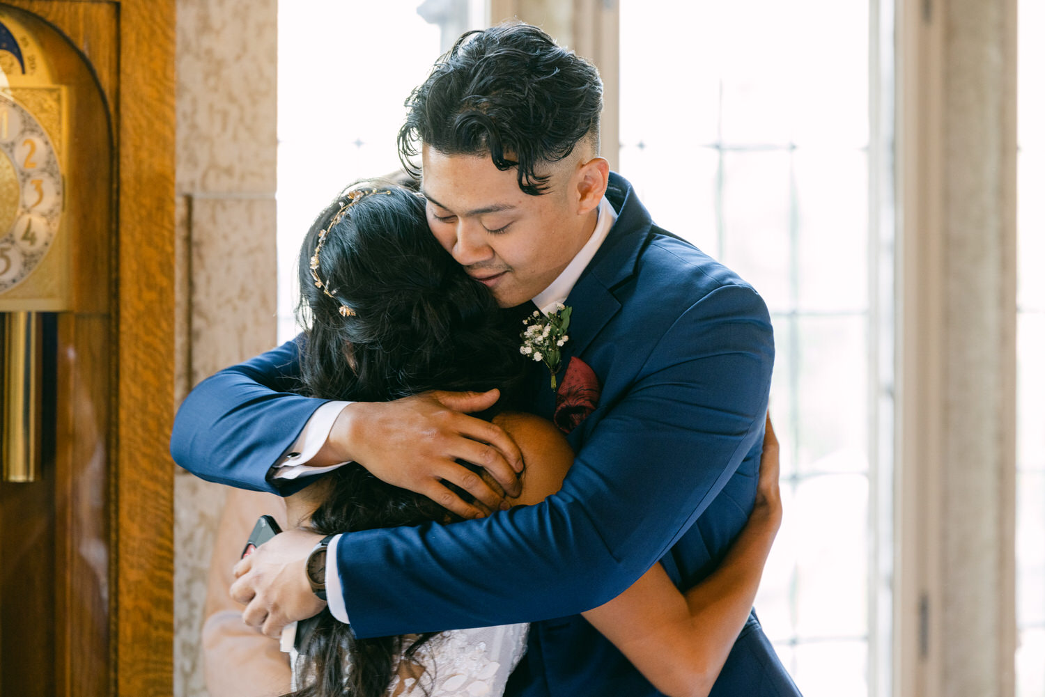 A joyful couple sharing a heartfelt embrace during their wedding celebration, surrounded by a cozy indoor setting.