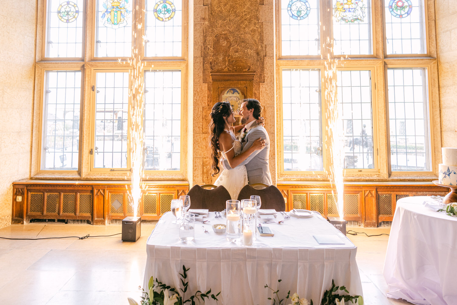 A couple shares a romantic moment during their wedding reception, surrounded by elegant decor and special effects.