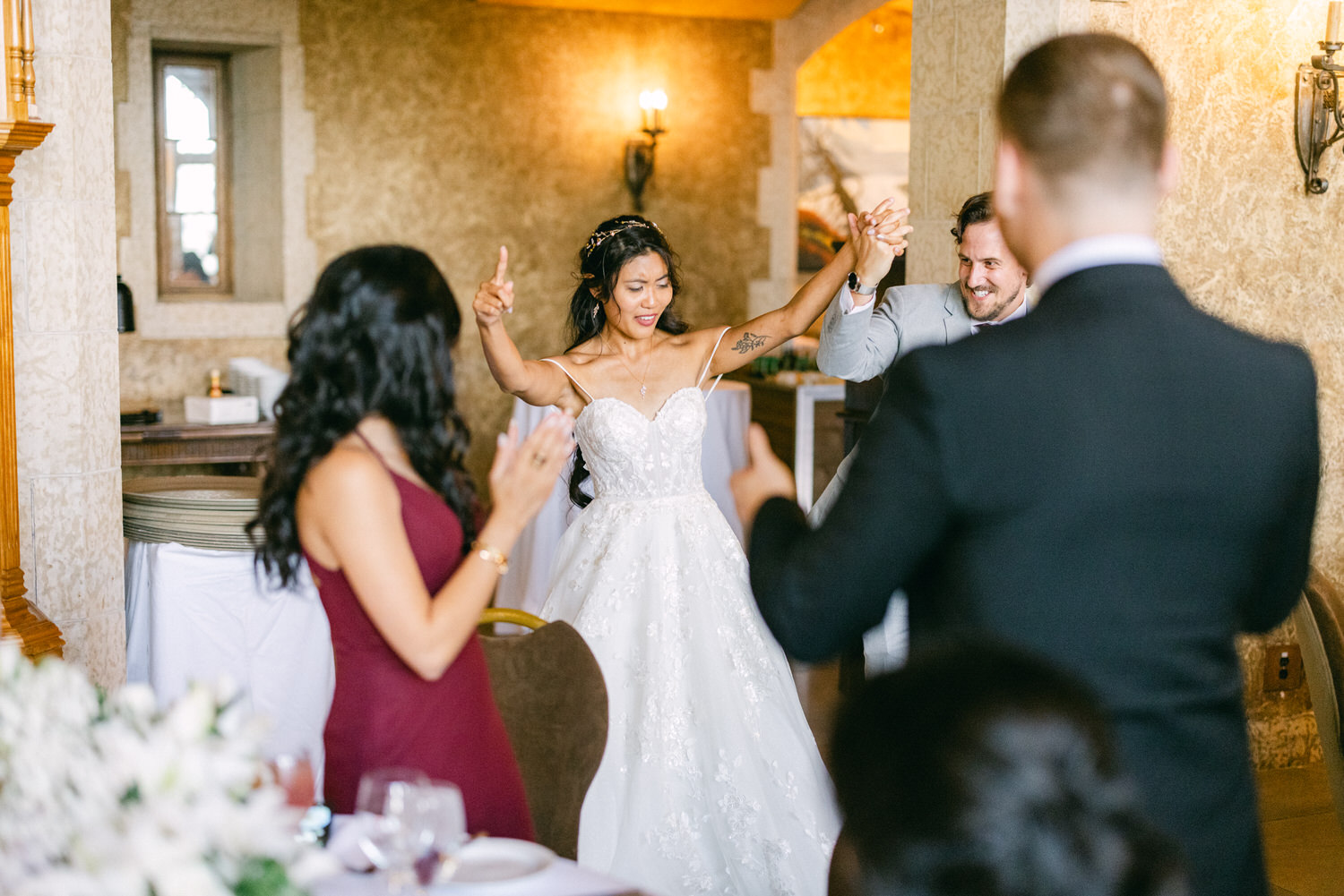 Bride and groom joyfully celebrate their wedding, surrounded by guests in an elegant venue.