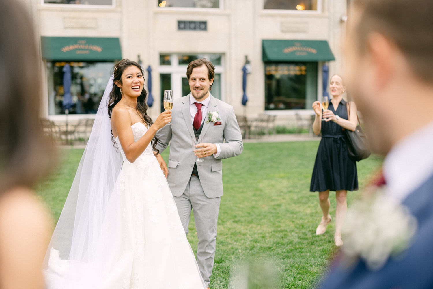 A bride and groom toast with champagne in a garden setting, surrounded by happy guests.