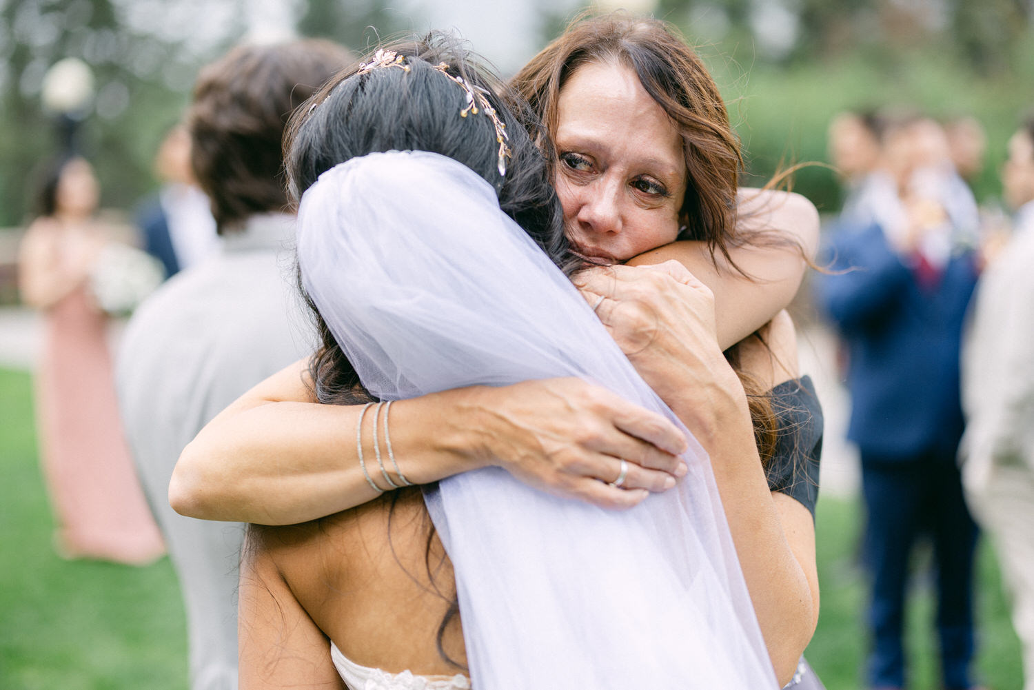 A heartfelt moment capturing a bride and her mother sharing a warm embrace during a wedding celebration, conveying love and connection.