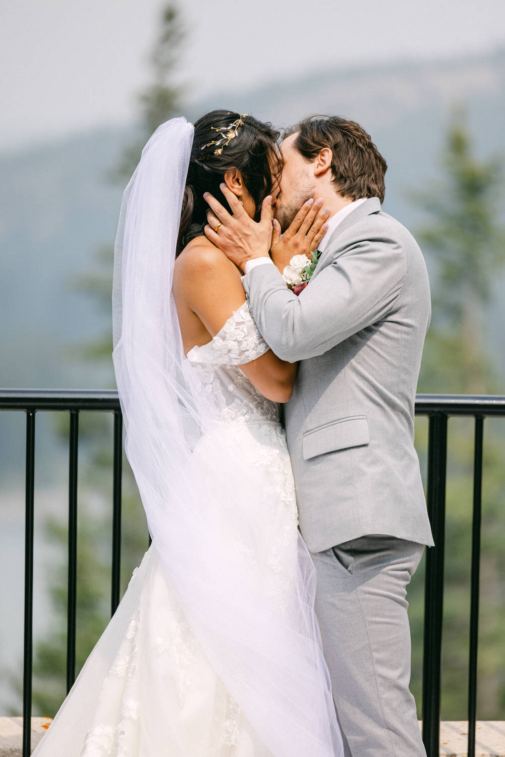 A bride and groom share a passionate kiss during their outdoor wedding ceremony, surrounded by beautiful natural scenery.