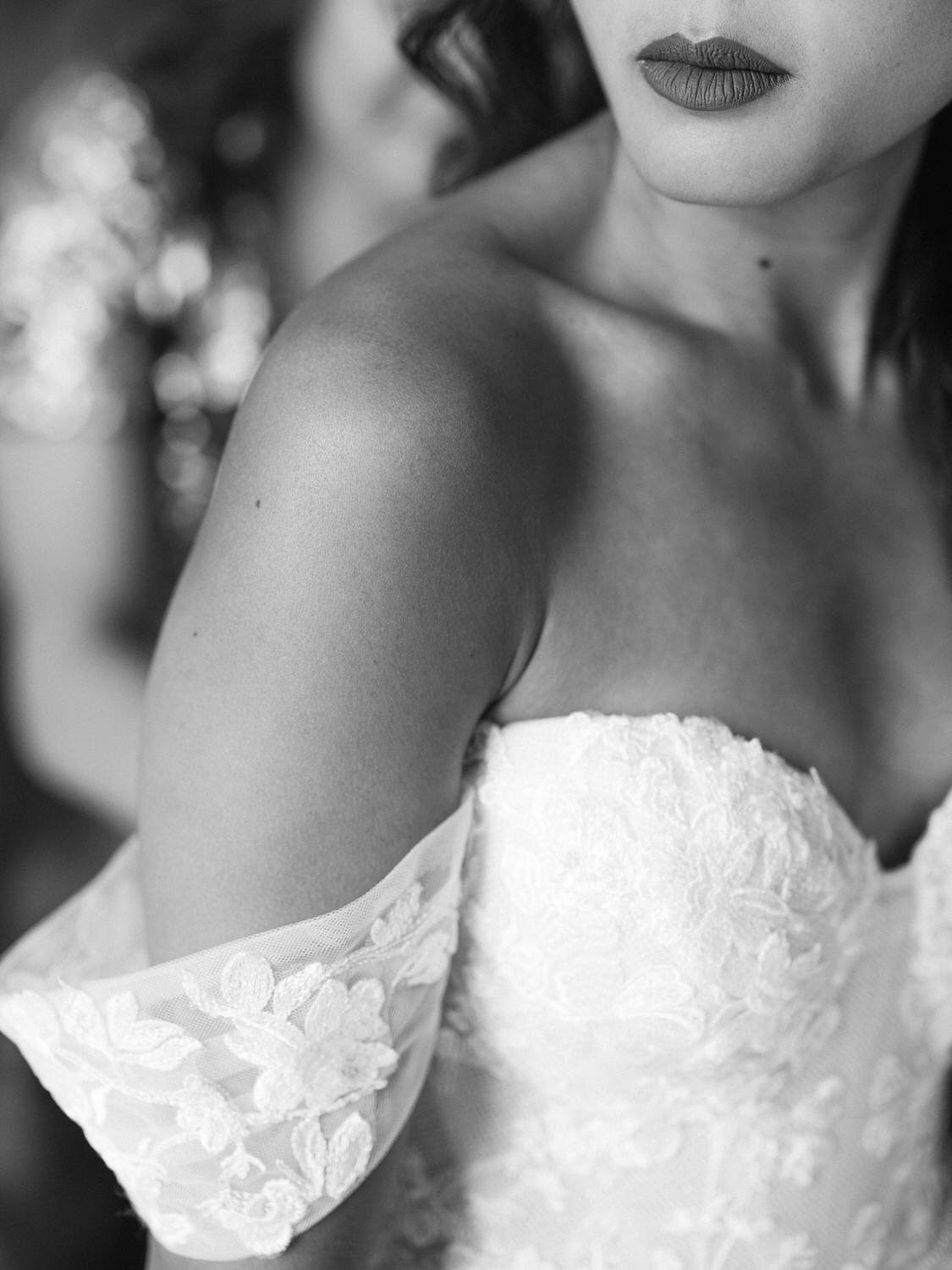 Close-up of a bride's shoulder adorned with delicate lace, showcasing the intricate details of her wedding dress and the soft texture of her skin.