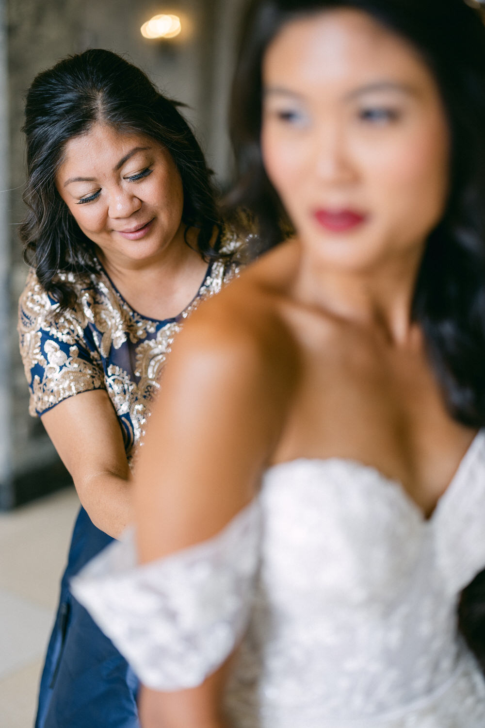 A bride's mother helps her daughter get ready, showcasing love and support during a special occasion.