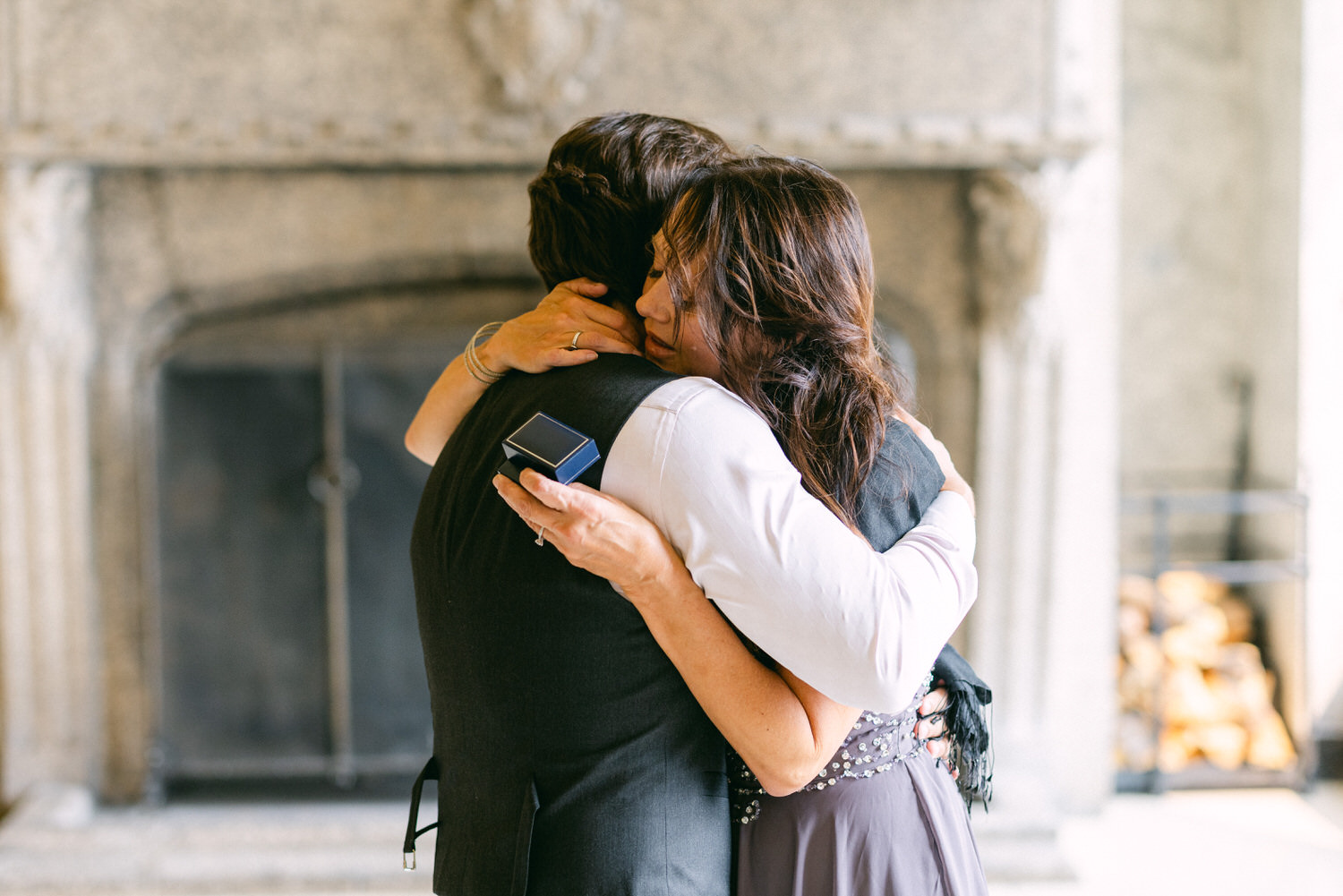 A heartfelt hug between two individuals, one holding a ring box, showcasing an intimate and joyous occasion.