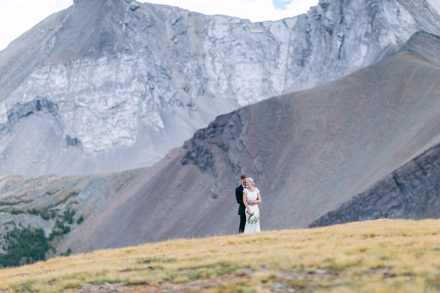 A couple embraces in a breathtaking mountain landscape, capturing a moment of love and serenity amidst majestic peaks.