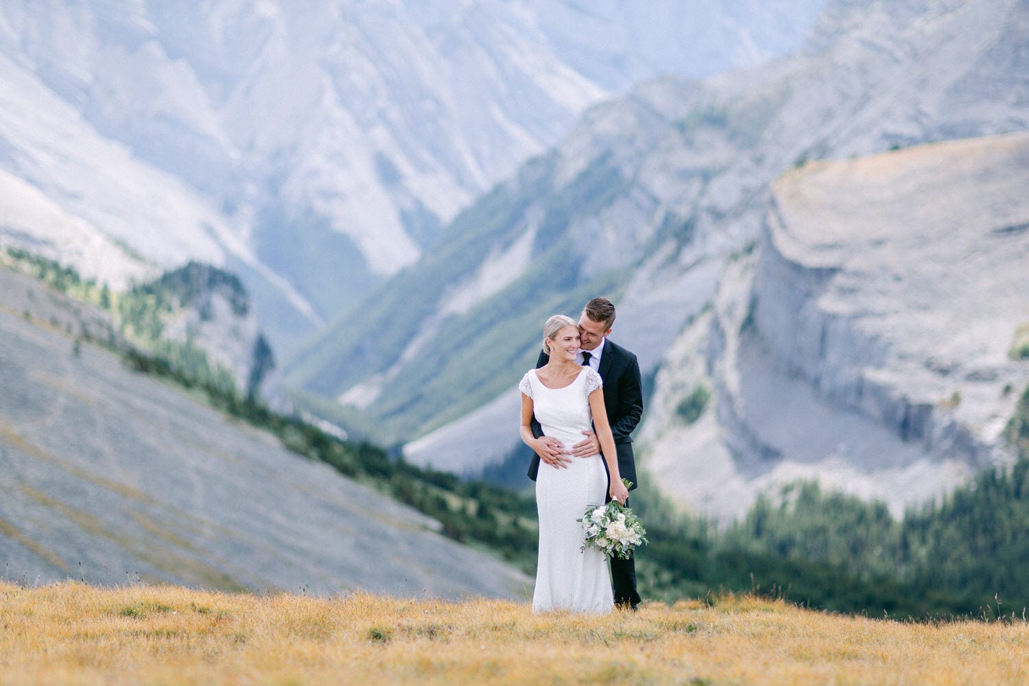 A bride and groom embrace in a stunning mountain landscape, capturing a moment of love against a backdrop of majestic peaks.