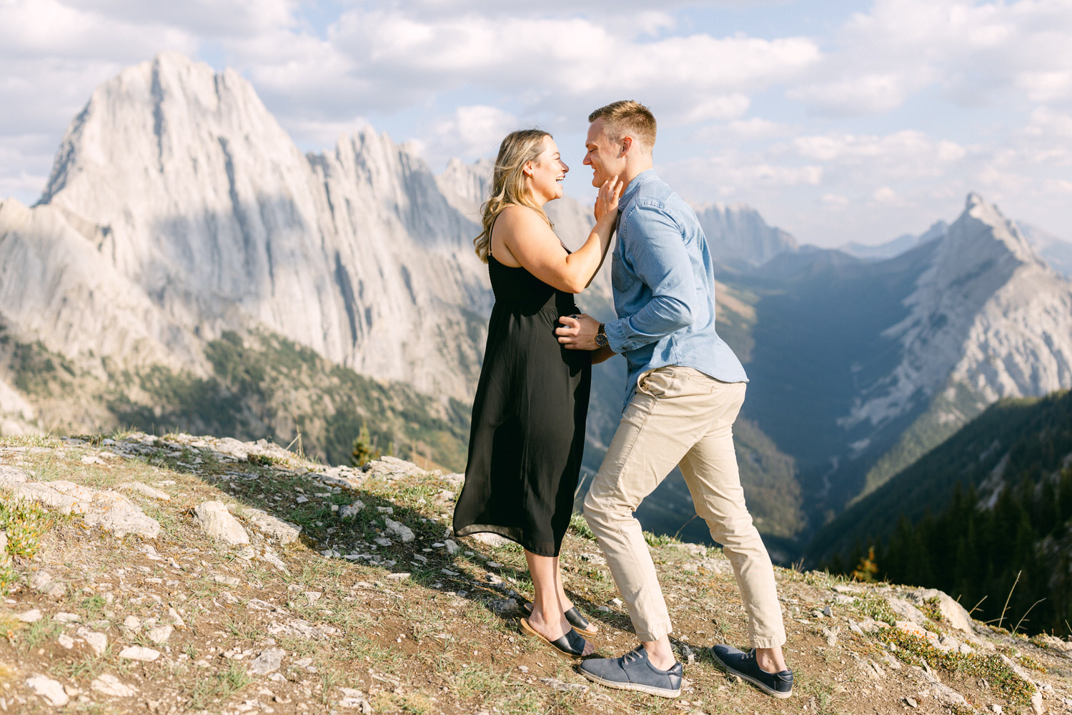 A couple enjoying a romantic moment on a mountain overlook with dramatic peaks in the background.