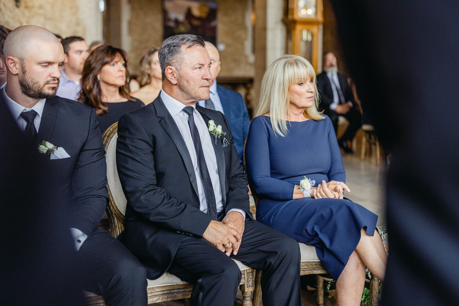 Guests seated calmly during a wedding ceremony, showcasing emotional expressions and elegant attire.