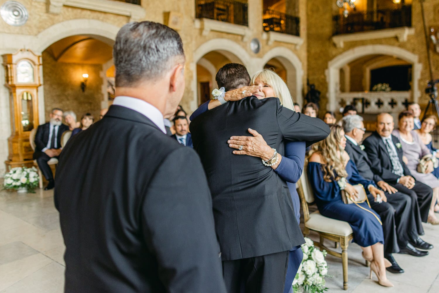 A heartfelt hug between a couple during a wedding ceremony, surrounded by seated guests witnessing the moment.