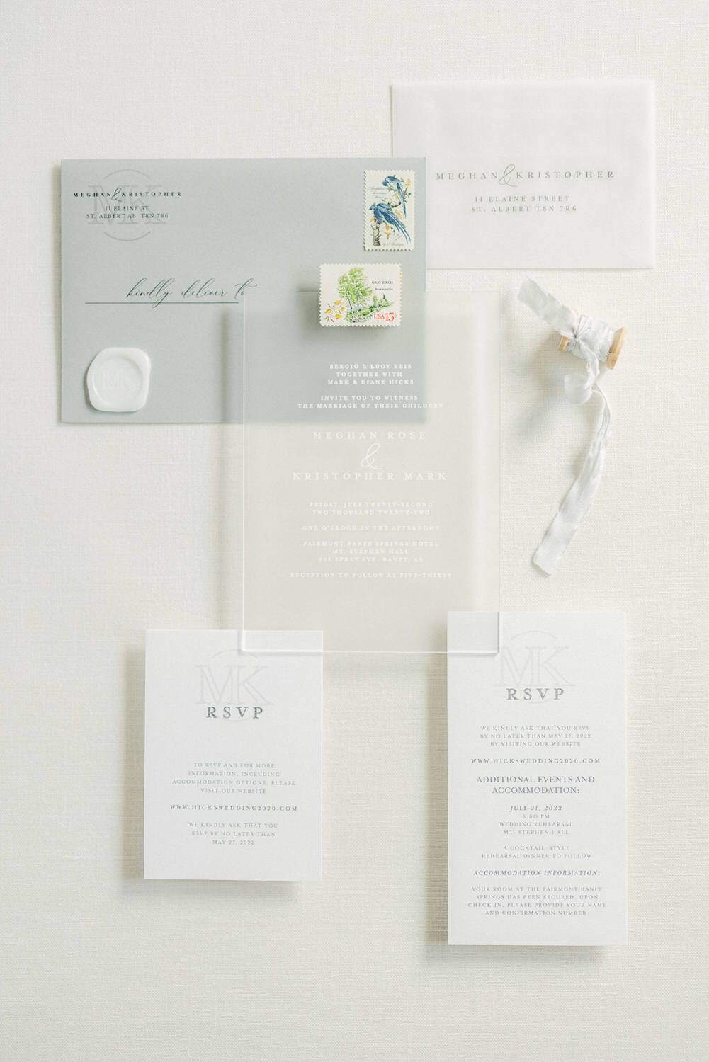 A beautifully arranged wedding invitation suite featuring a light blue envelope, clear RSVP card, and decorative stamps, showcasing an elegant design perfect for a special occasion.